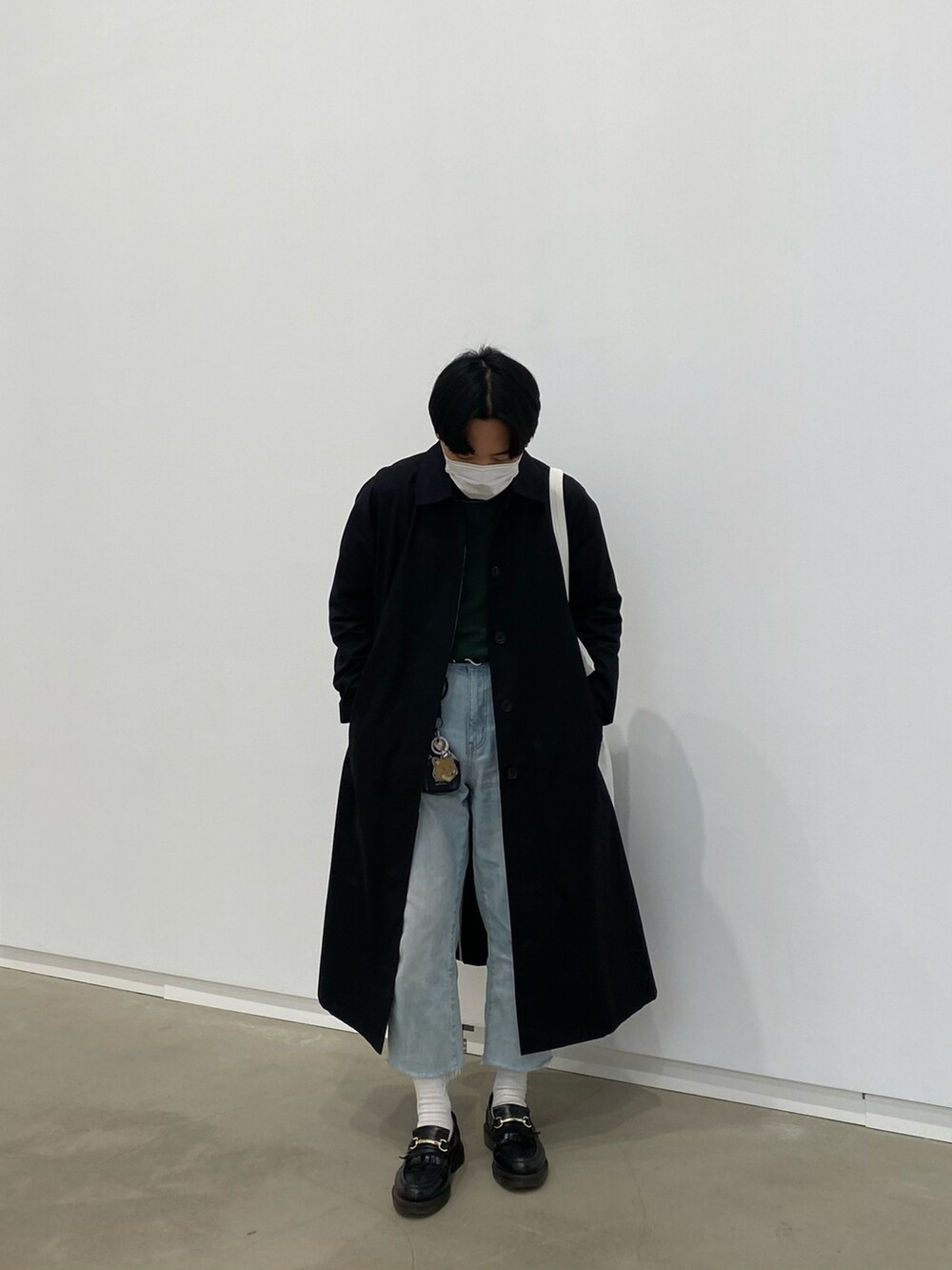 ブラック系のステンカラーコート、グリーン系のスウェット、ホワイト系のトートバッグを着用したメンズの春コーディネートの2枚目の写真