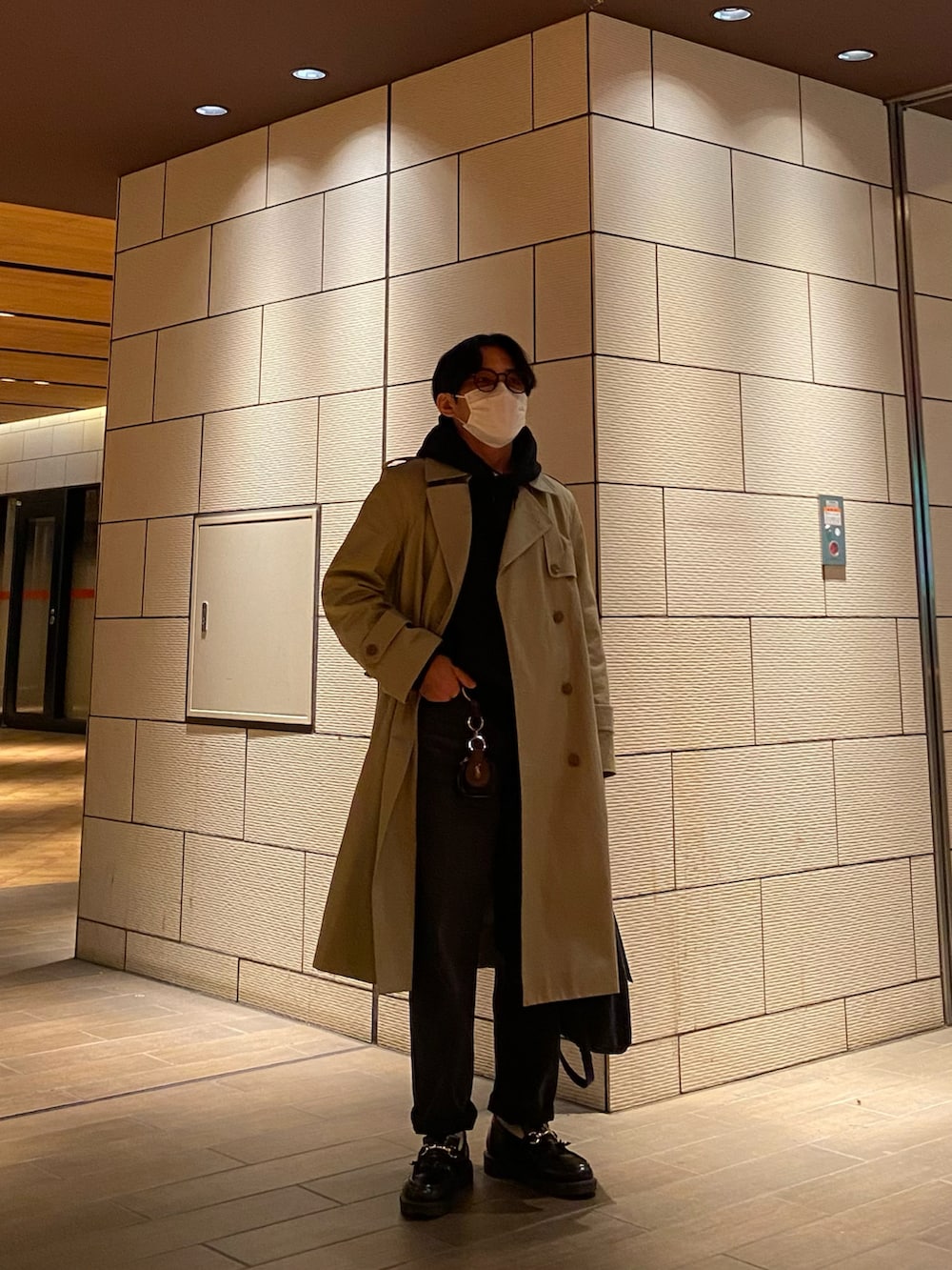 ブラック系のパーカー、ブラック系のローファー、ベージュ系のトレンチコートを着用したメンズの冬コーディネートの5枚目の写真