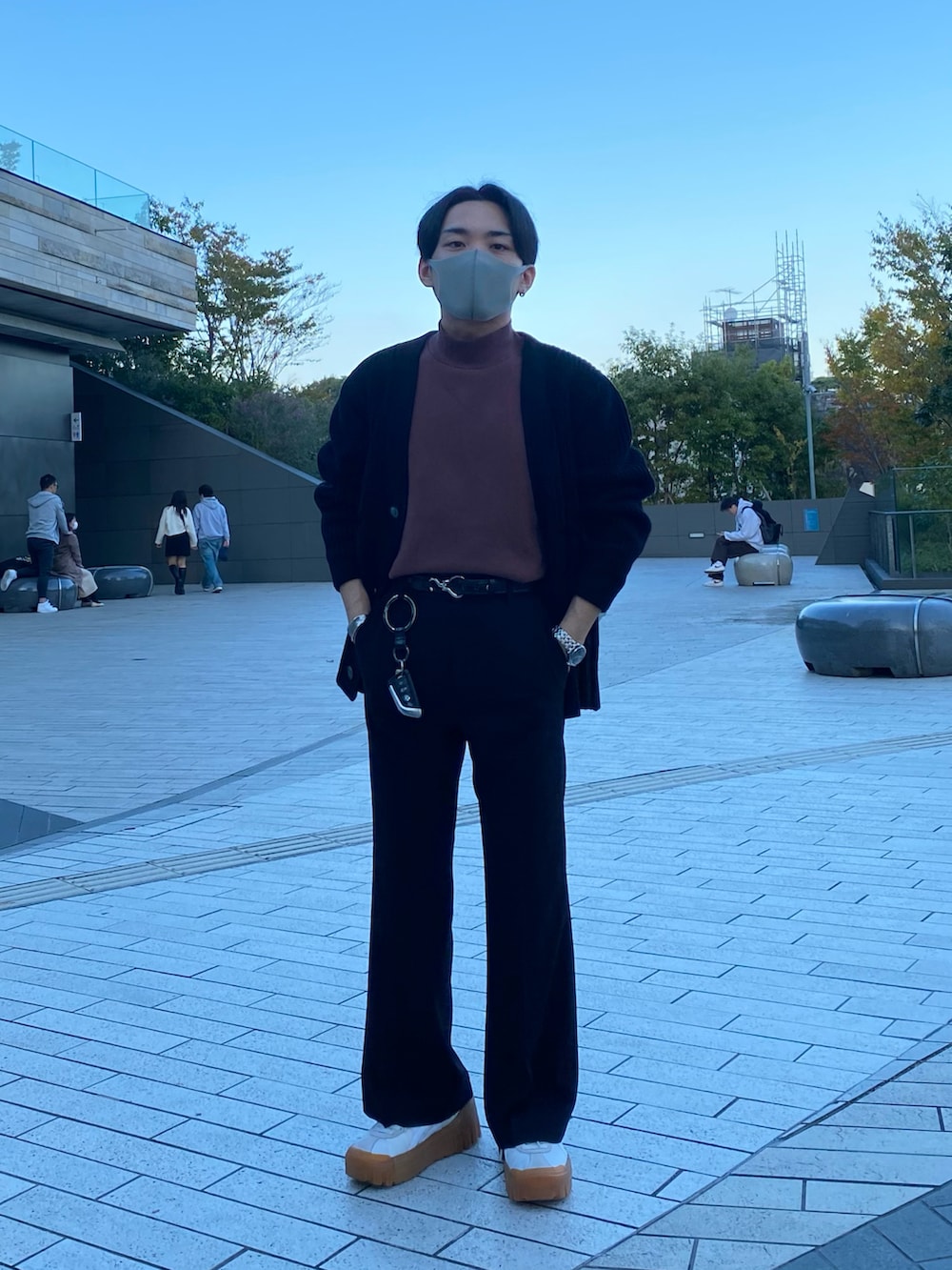 ブラック系のダウンジャケット/コート、ブラック系のカーディガン/ボレロ、レッド系のTシャツ/カットソーを着用したメンズの秋コーディネートの3枚目の写真