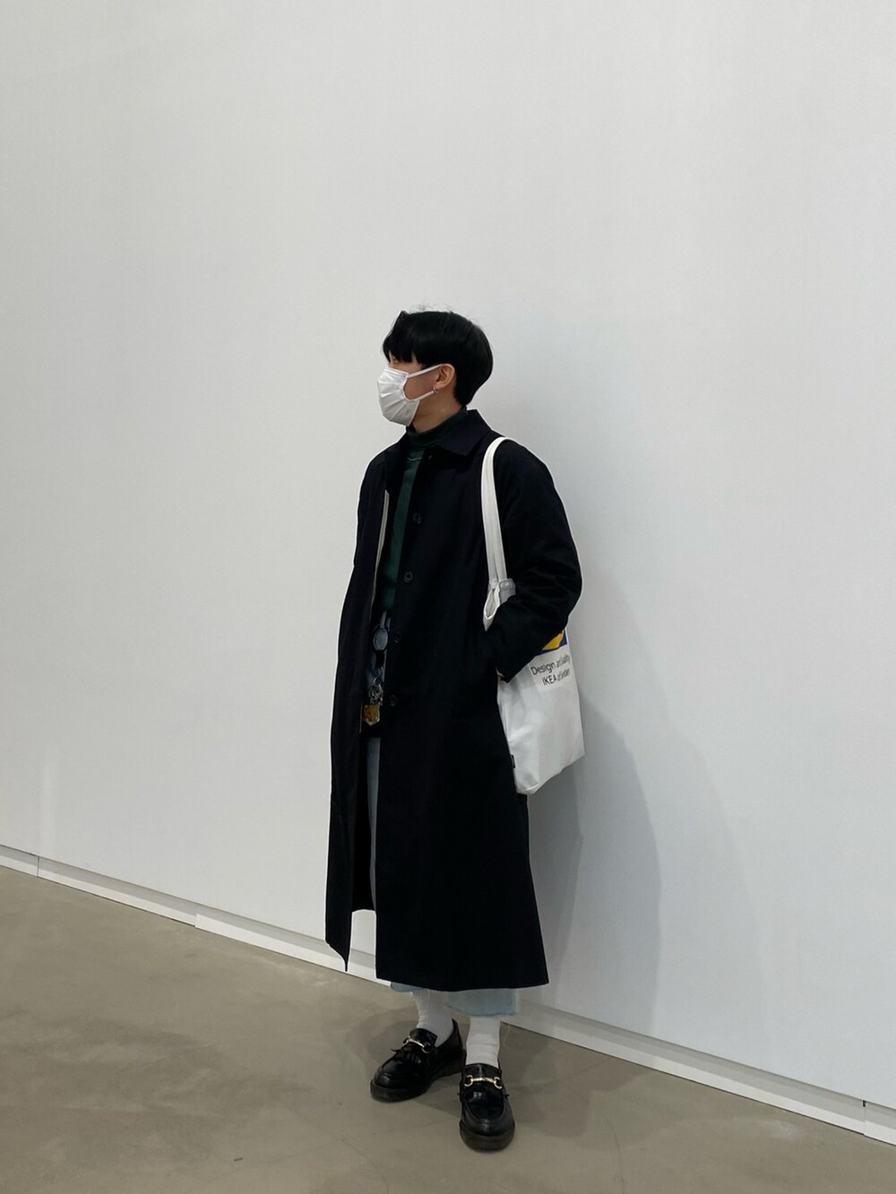 ブラック系のステンカラーコート、グリーン系のスウェット、ホワイト系のトートバッグを着用したメンズの春コーディネートの3枚目の写真