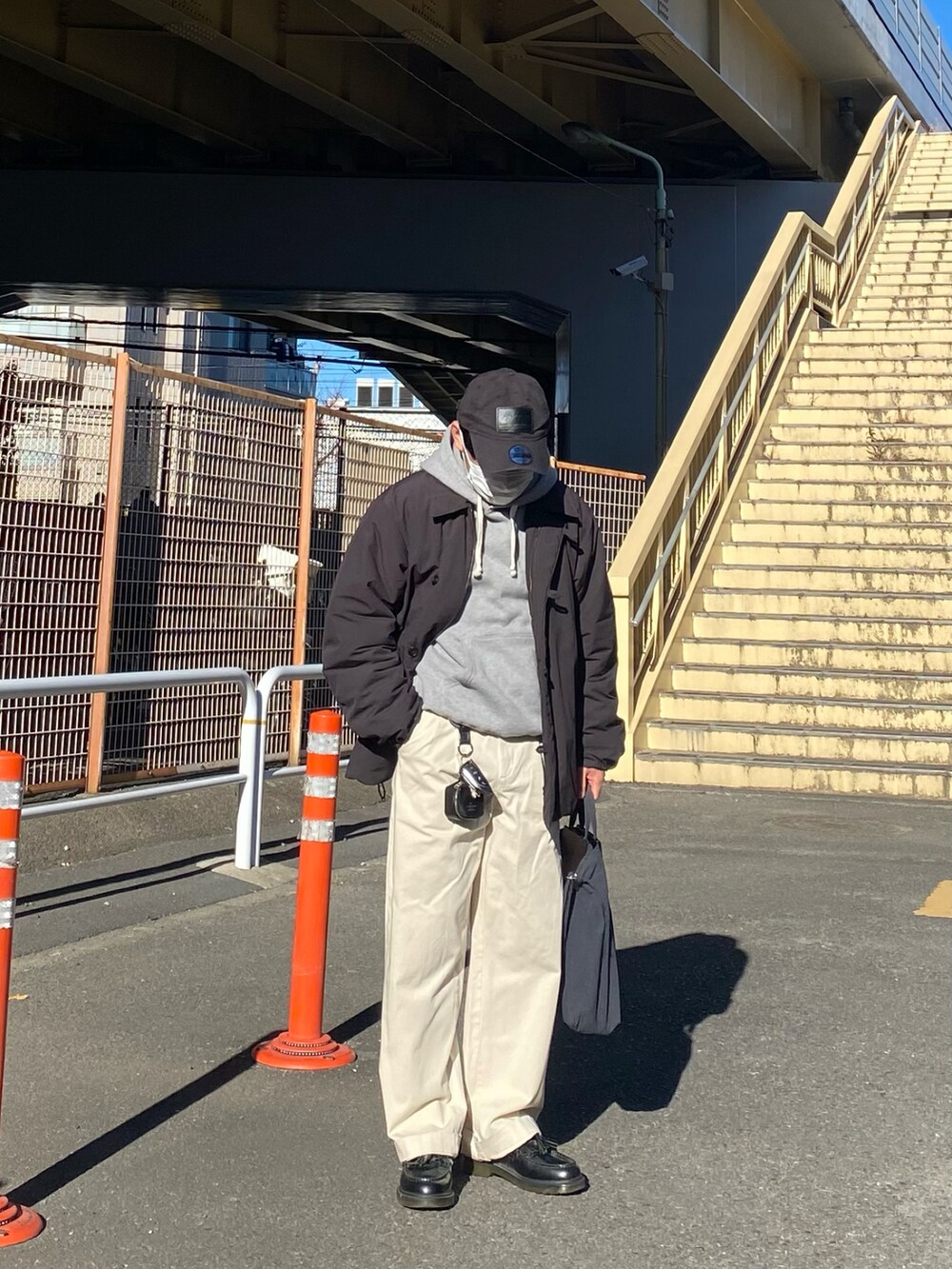 ブラック系のダウンジャケット/コート、グレー系のパーカー、ホワイト系のチノパンツを着用したメンズの冬コーディネートの2枚目の写真
