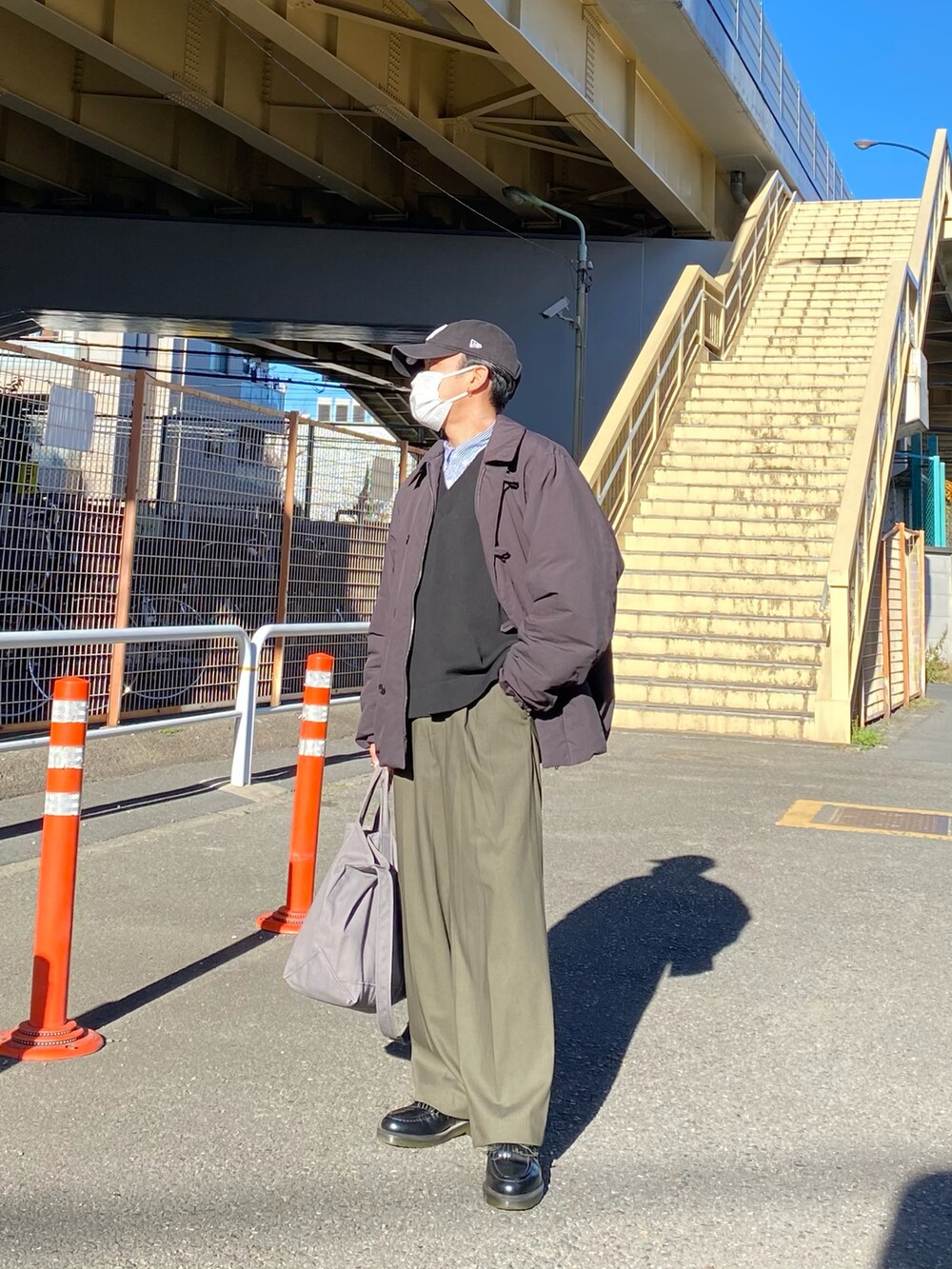 ブラック系のダウンジャケット/コート、ブラック系のベスト、ブルー系のシャツ/ブラウスを着用したメンズの冬コーディネートの3枚目の写真