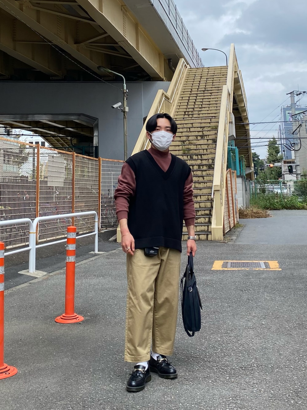 ブラック系のベスト、レッド系のTシャツ/カットソー、ベージュ系のチノパンツを着用したメンズの秋コーディネートの4枚目の写真