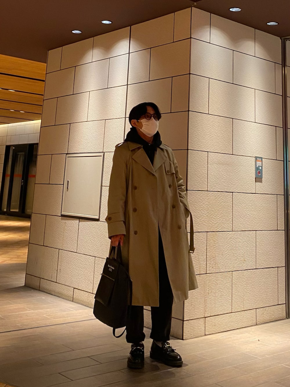 ブラック系のパーカー、ブラック系のローファー、ベージュ系のトレンチコートを着用したメンズの冬コーディネートの3枚目の写真