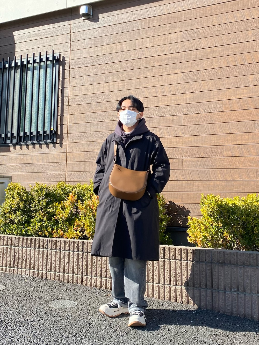 ブラック系のモッズコート、グレー系のパーカー、ブラウン系のバッグを着用したメンズの春コーディネートの2枚目の写真