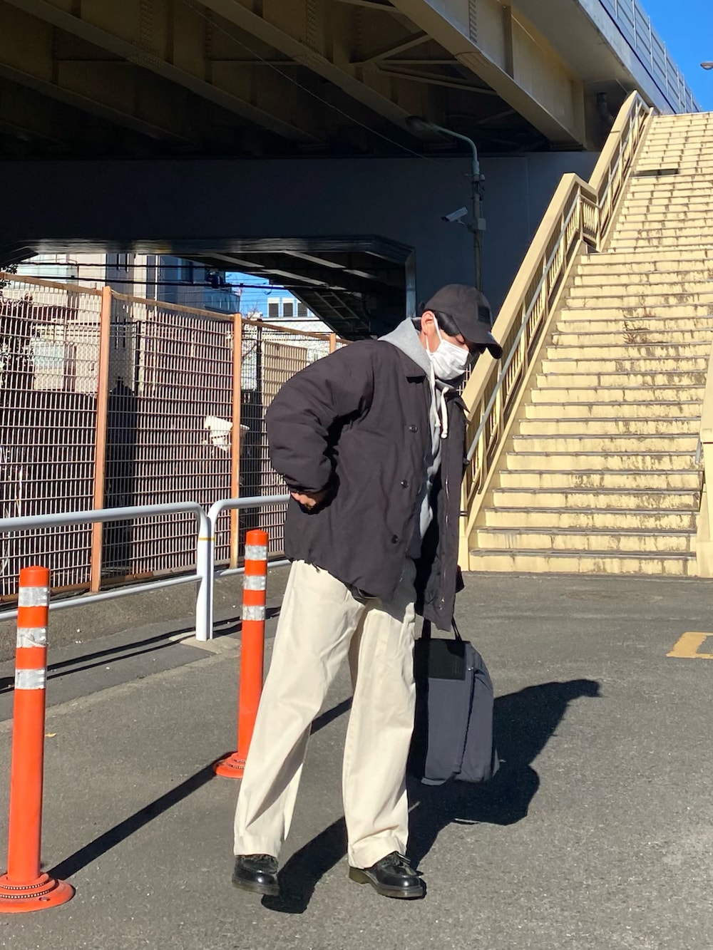 ブラック系のダウンジャケット/コート、グレー系のパーカー、ホワイト系のチノパンツを着用したメンズの冬コーディネートの3枚目の写真