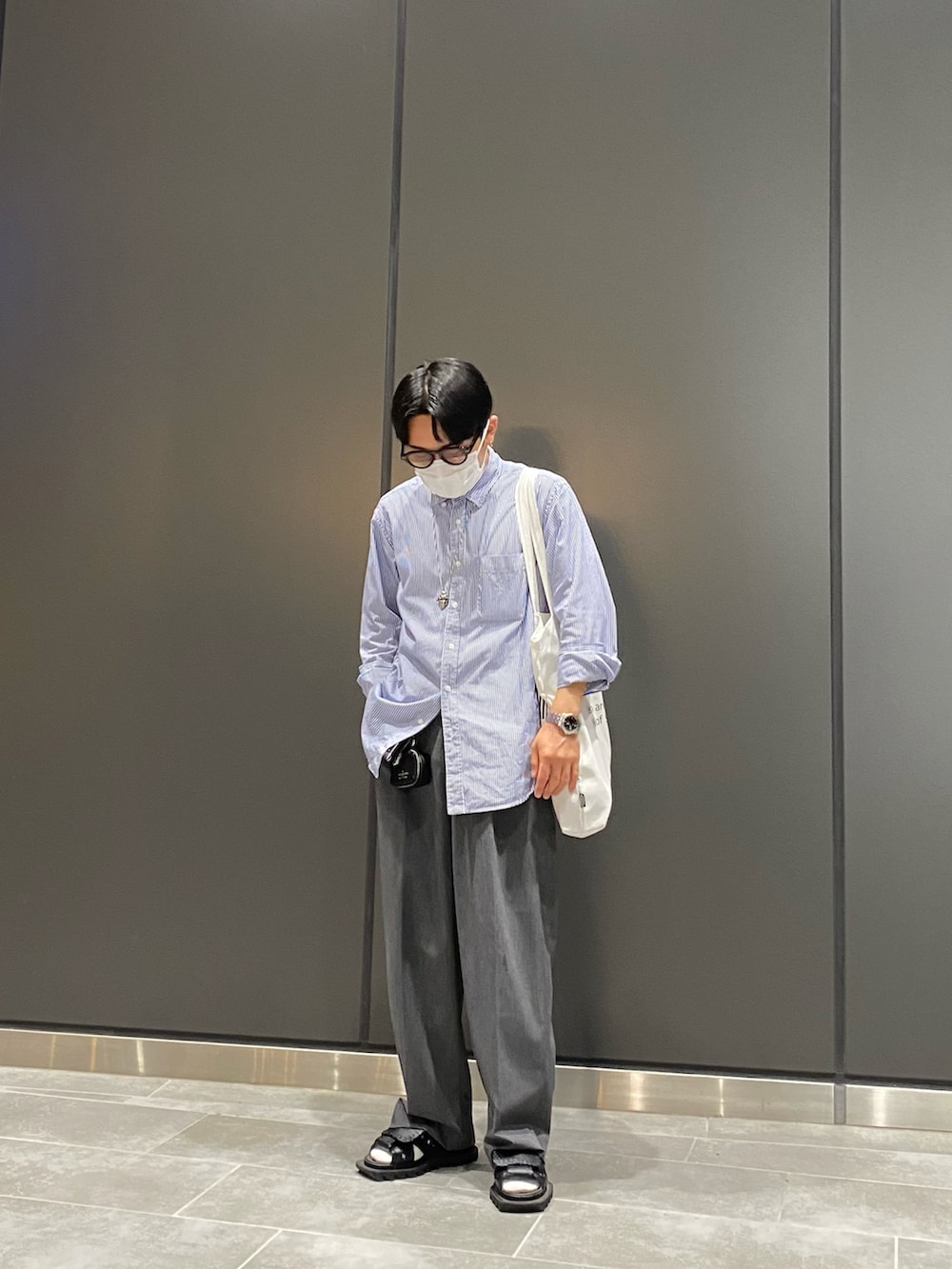 ブルー系のシャツ/ブラウス、ホワイト系のトートバッグ、ブラック系のサンダルを着用したメンズの夏コーディネートの3枚目の写真