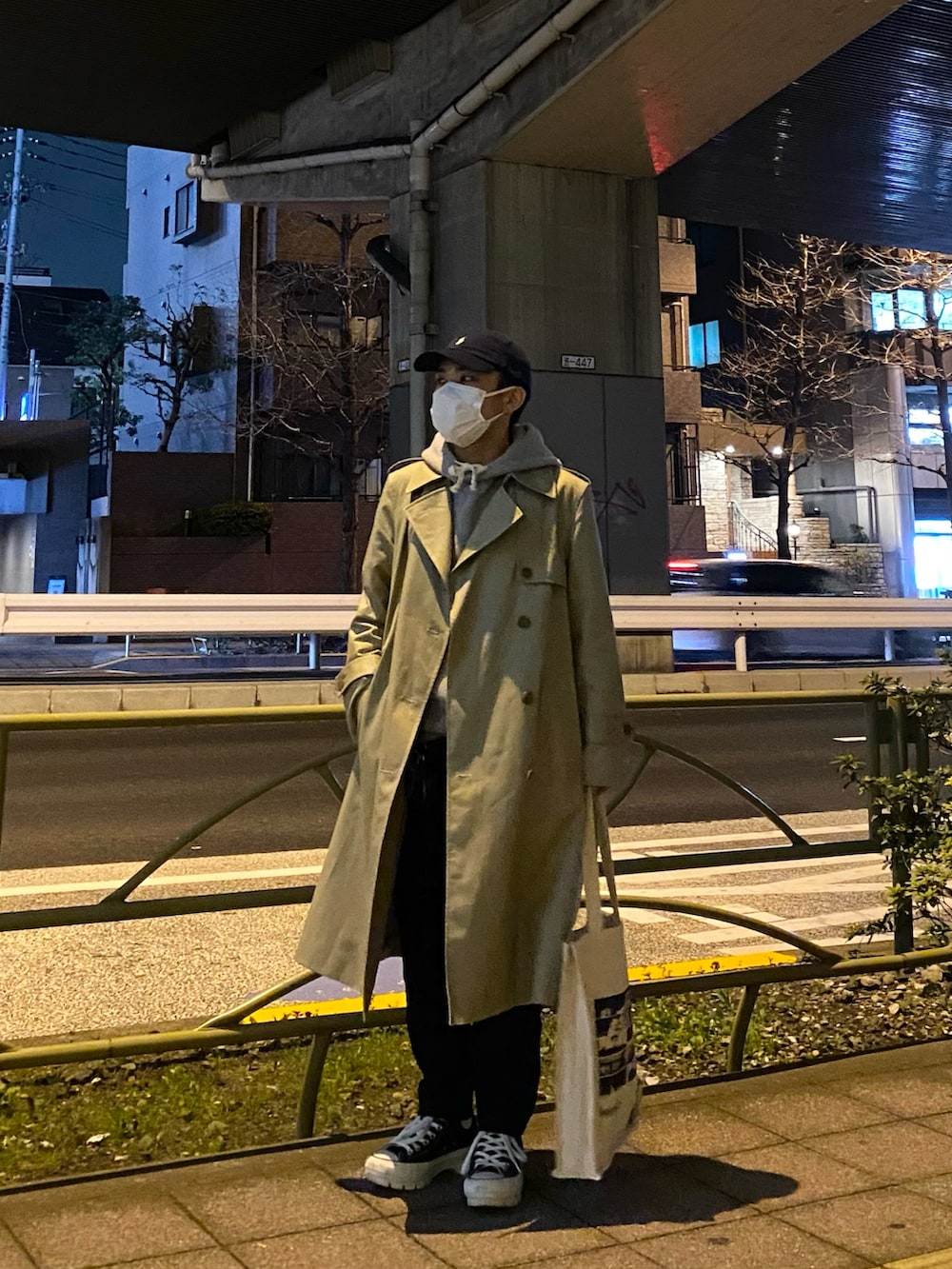 ベージュ系のトレンチコート、グレー系のパーカー、ホワイト系のトートバッグを着用したメンズの春コーディネートの4枚目の写真