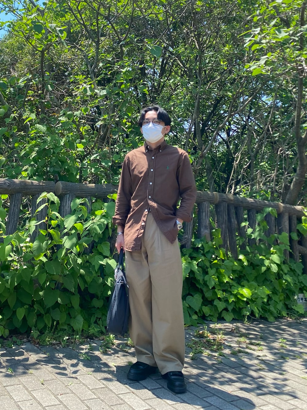 ブラウン系のシャツ/ブラウス、ベージュ系のチノパンツ、ブラック系のトートバッグを着用したメンズの春コーディネートの5枚目の写真