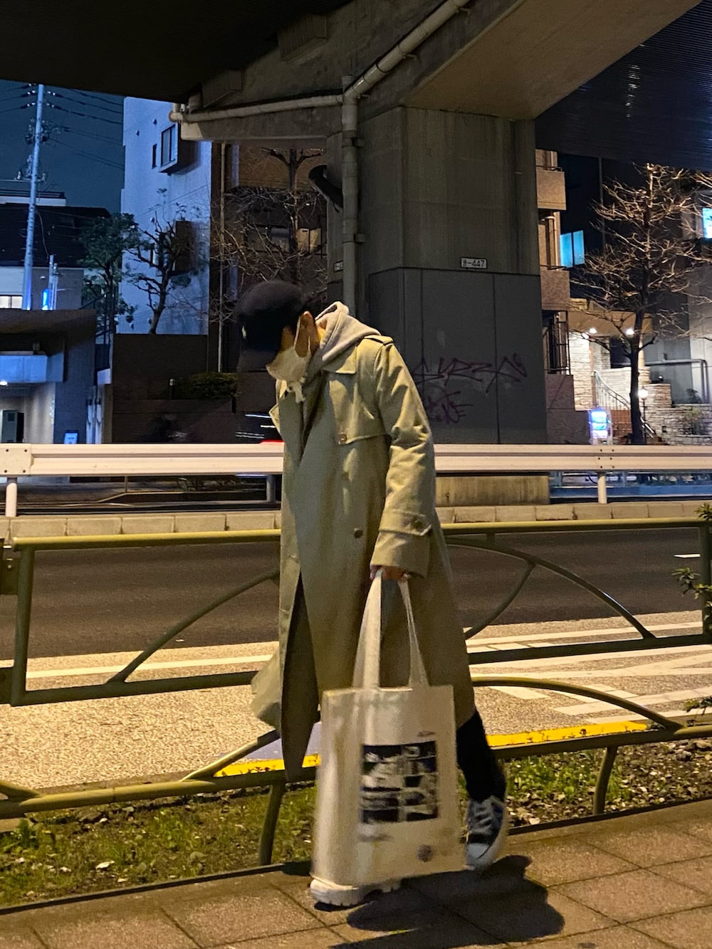 ベージュ系のトレンチコート、グレー系のパーカー、ホワイト系のトートバッグを着用したメンズの春コーディネートの5枚目の写真