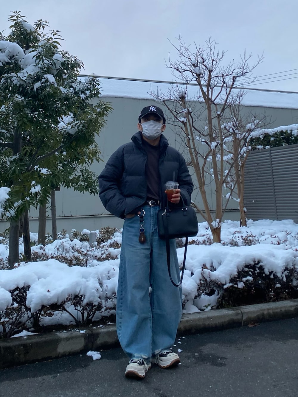 ブルー系のデニムパンツ、ブラック系のスニーカー、パープル系のTシャツ/カットソーを着用したメンズの冬コーディネートの3枚目の写真