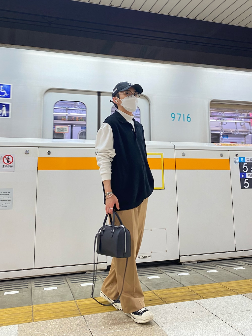 ブラック系のベスト、ホワイト系のTシャツ/カットソー、ベージュ系のスラックスを着用したメンズの春コーディネートの3枚目の写真