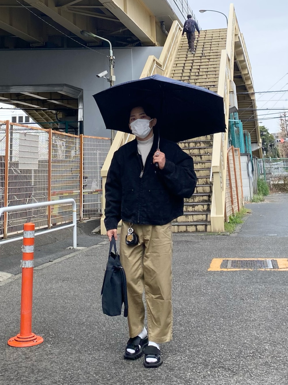 ブラック系のブルゾン、ホワイト系のTシャツ/カットソー、ベージュ系のチノパンツを着用したメンズの春コーディネートの5枚目の写真