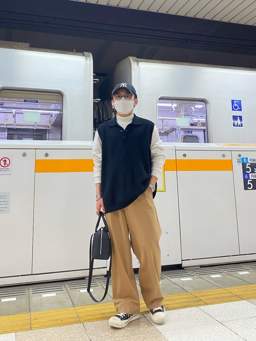 ブラック系のベスト、ホワイト系のTシャツ/カットソー、ベージュ系のスラックスを着用したメンズの春コーディネートの4枚目の写真