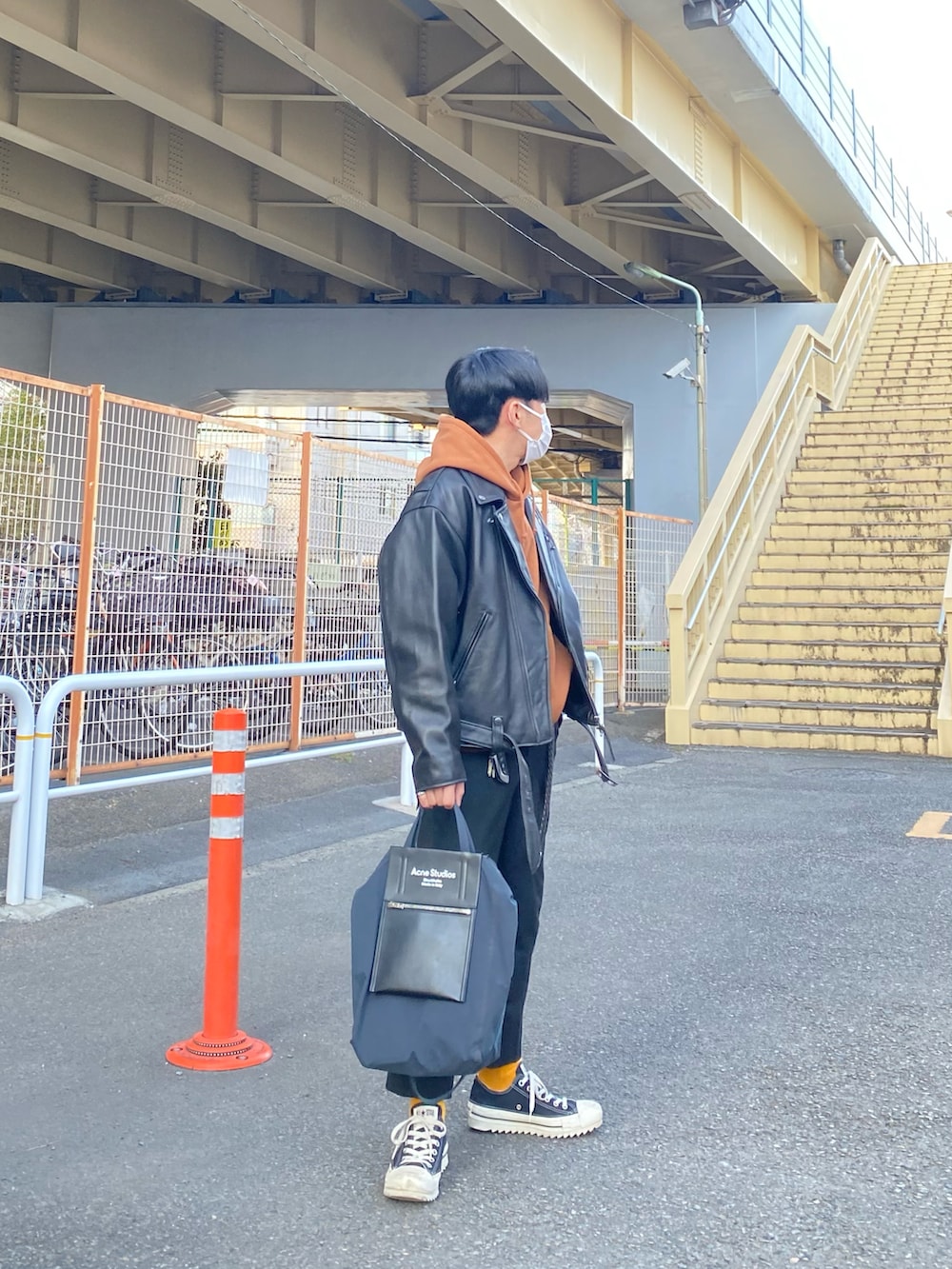 ブラック系のライダースジャケット、ブラウン系のパーカー、ブラック系のスラックスを着用したメンズの冬コーディネートの2枚目の写真