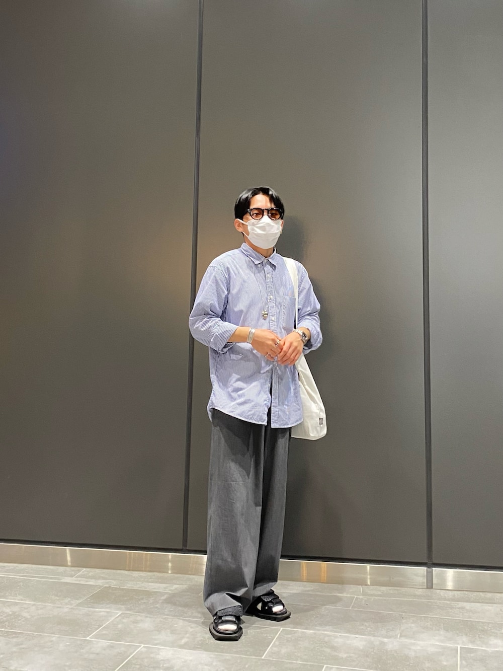 ブルー系のシャツ/ブラウス、ホワイト系のトートバッグ、ブラック系のサンダルを着用したメンズの夏コーディネートの4枚目の写真