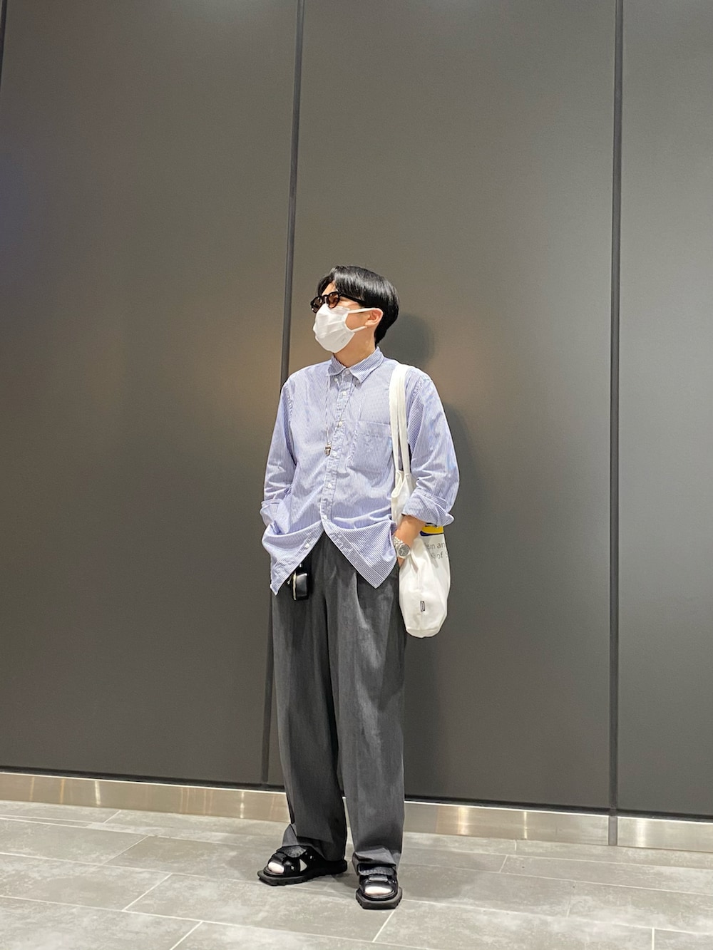 ブルー系のシャツ/ブラウス、ホワイト系のトートバッグ、ブラック系のサンダルを着用したメンズの夏コーディネートの2枚目の写真