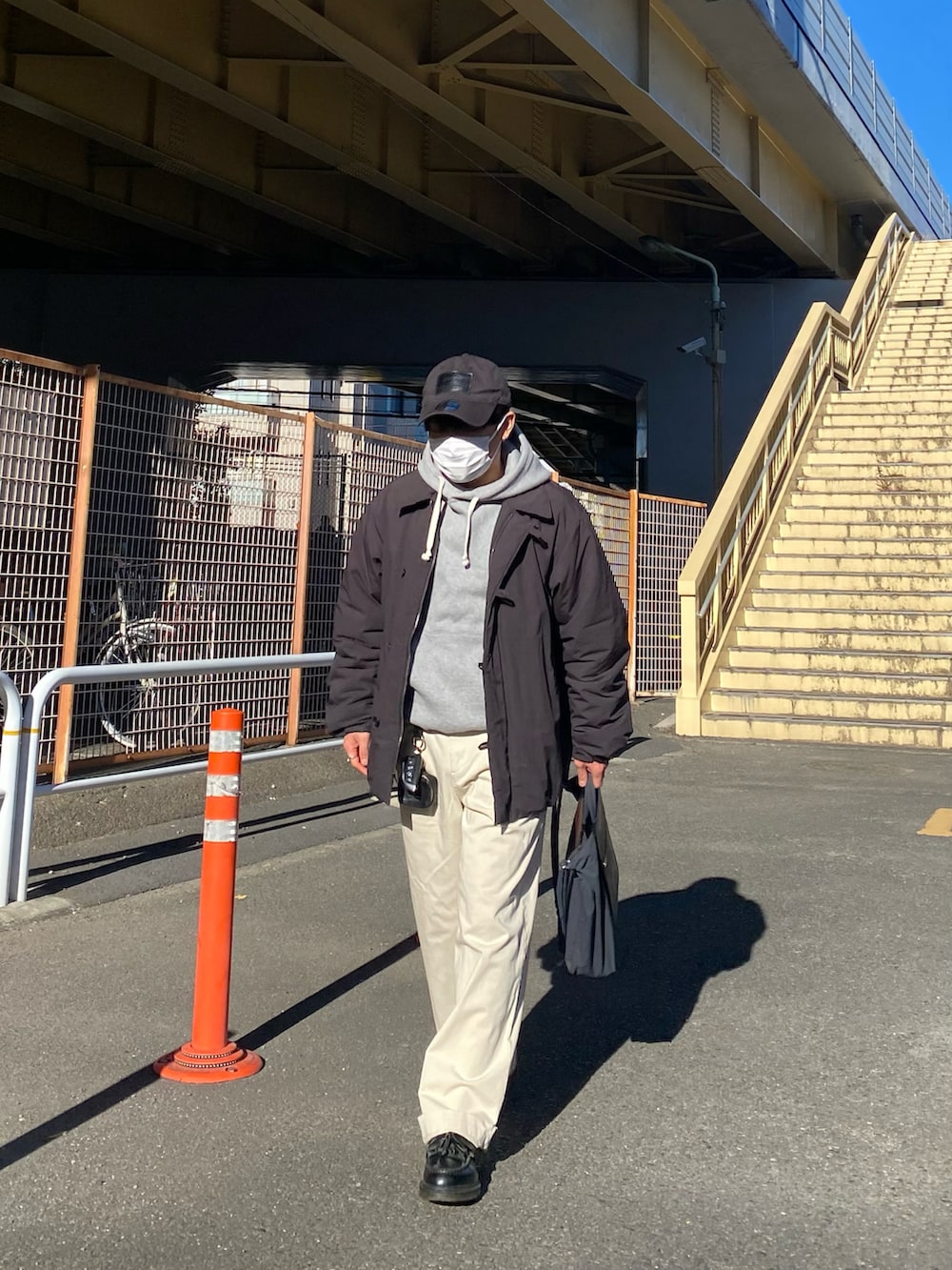 ブラック系のダウンジャケット/コート、グレー系のパーカー、ホワイト系のチノパンツを着用したメンズの冬コーディネートの5枚目の写真