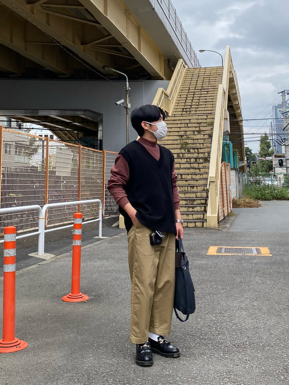 ブラック系のベスト、レッド系のTシャツ/カットソー、ベージュ系のチノパンツを着用したメンズの秋コーディネートの3枚目の写真