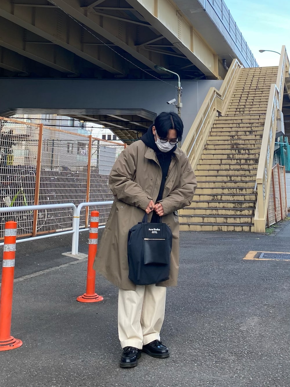 ブラウン系のモッズコート、ブラック系のパーカー、ホワイト系のチノパンツを着用したメンズの冬コーディネートの4枚目の写真