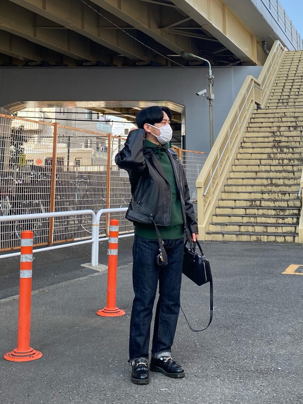 ブラック系のライダースジャケット、グリーン系のパーカー、ブルー系のデニムパンツを着用したメンズの春コーディネートの4枚目の写真