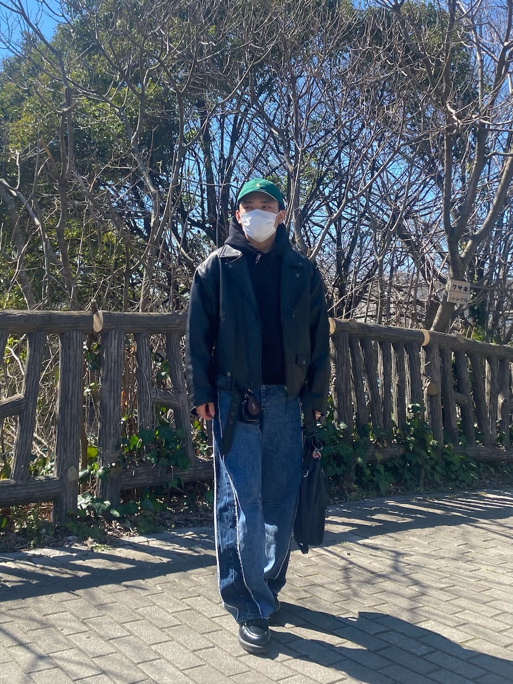 ブラック系のライダースジャケット、ブラック系のパーカー、ブルー系のデニムパンツを着用したメンズの春コーディネートの5枚目の写真