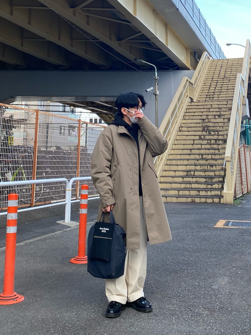 ブラウン系のモッズコート、ブラック系のパーカー、ホワイト系のチノパンツを着用したメンズの冬コーディネートの3枚目の写真