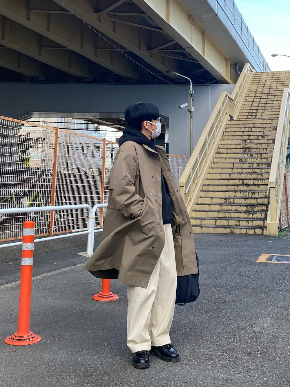 ブラウン系のモッズコート、ブラック系のパーカー、ホワイト系のチノパンツを着用したメンズの冬コーディネートの5枚目の写真