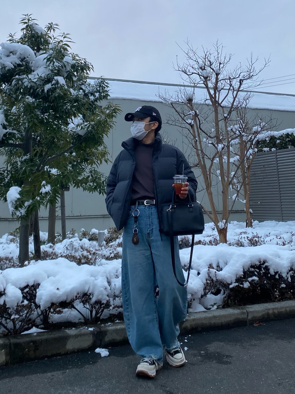 ブルー系のデニムパンツ、ブラック系のスニーカー、パープル系のTシャツ/カットソーを着用したメンズの冬コーディネートの4枚目の写真