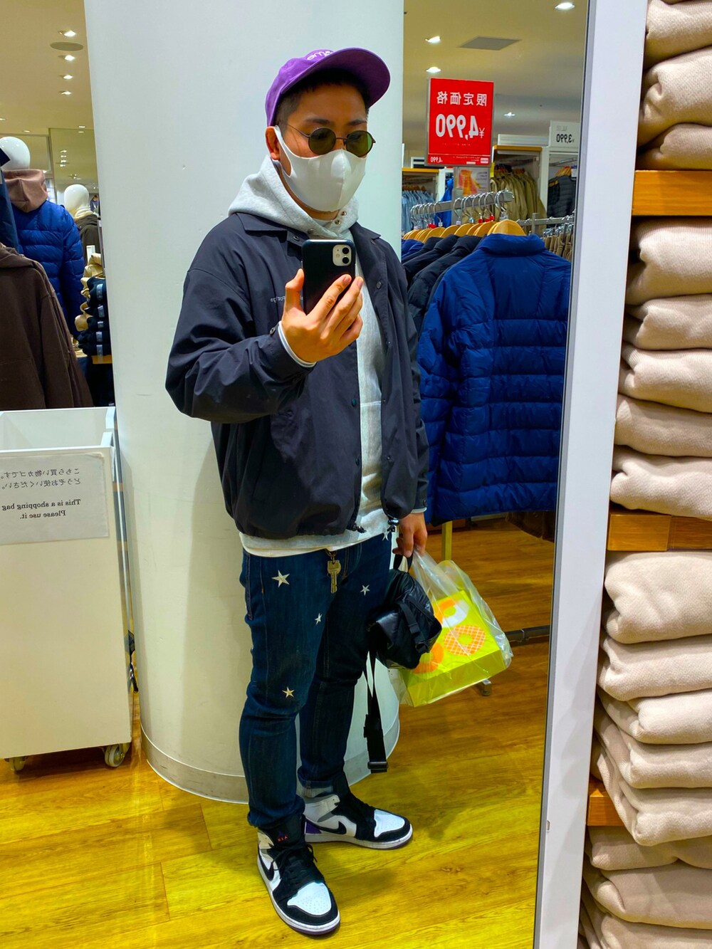 ブルー系のデニムパンツ、ブラック系のナイロンジャケット、グレー系のパーカーを着用したメンズの冬コーディネートの2枚目の写真