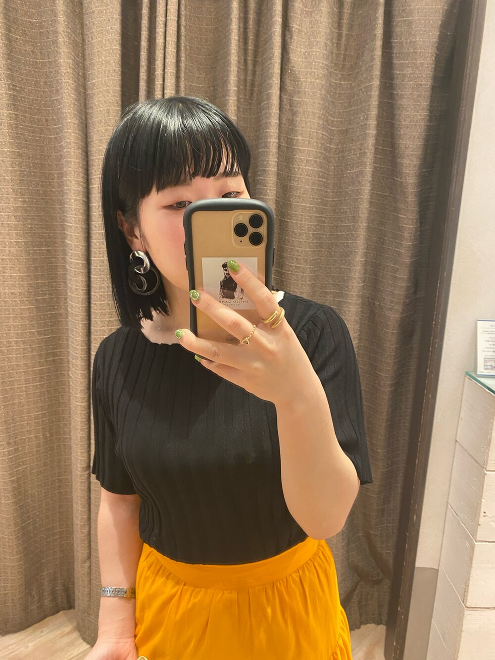 ブラック系のニット/セーター、オレンジ系のスカート、シルバー系のその他シューズを着用したレディースの春コーディネートの3枚目の写真