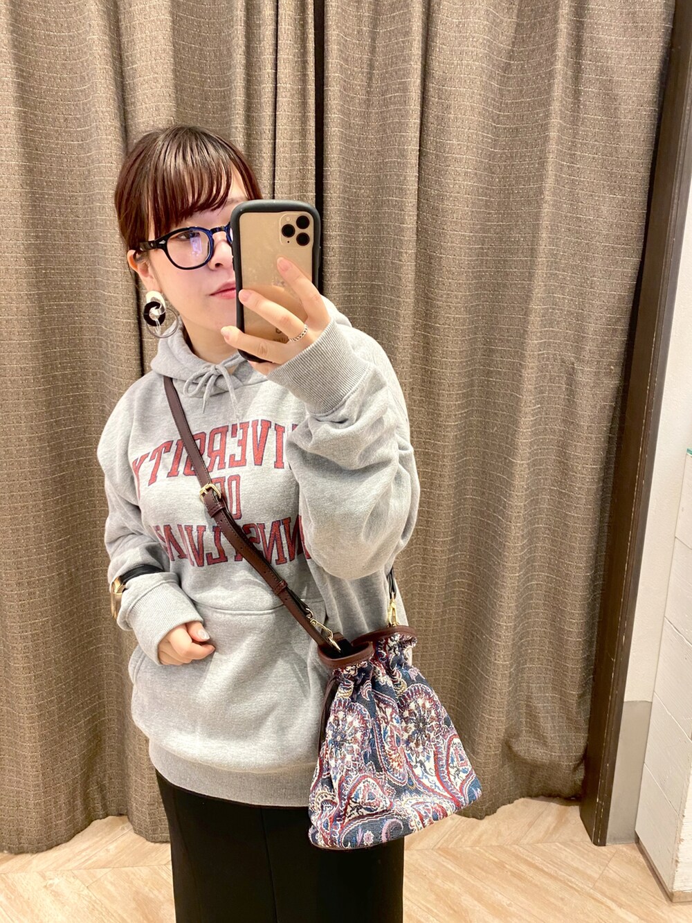 ブルー系のショルダーバッグ、ブラック系のスカート、グレー系のパーカーを着用したレディースの冬コーディネートの2枚目の写真