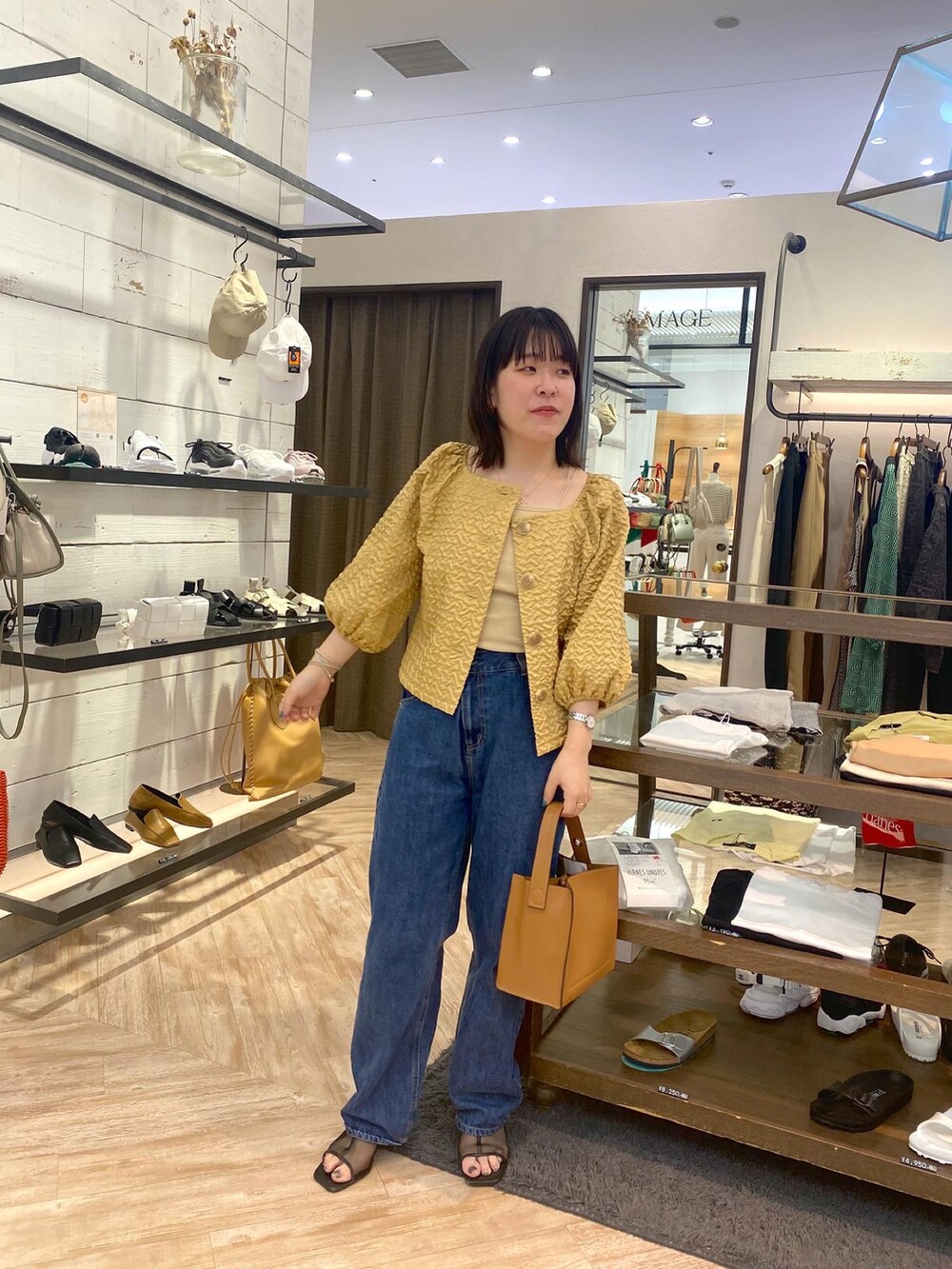 イエロー系のシャツ/ブラウス、ベージュ系のキャミソール、ブルー系のデニムパンツを着用したレディースの夏コーディネートの2枚目の写真