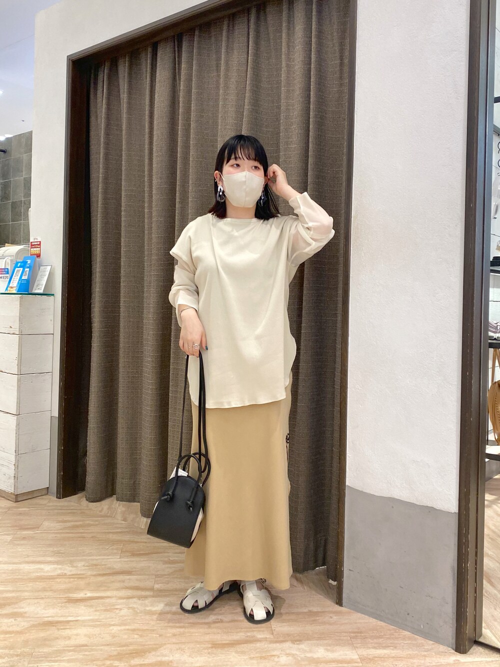 ベージュ系のTシャツ/カットソー、ベージュ系のスカート、ホワイト系のサンダルを着用したレディースの春コーディネートの2枚目の写真