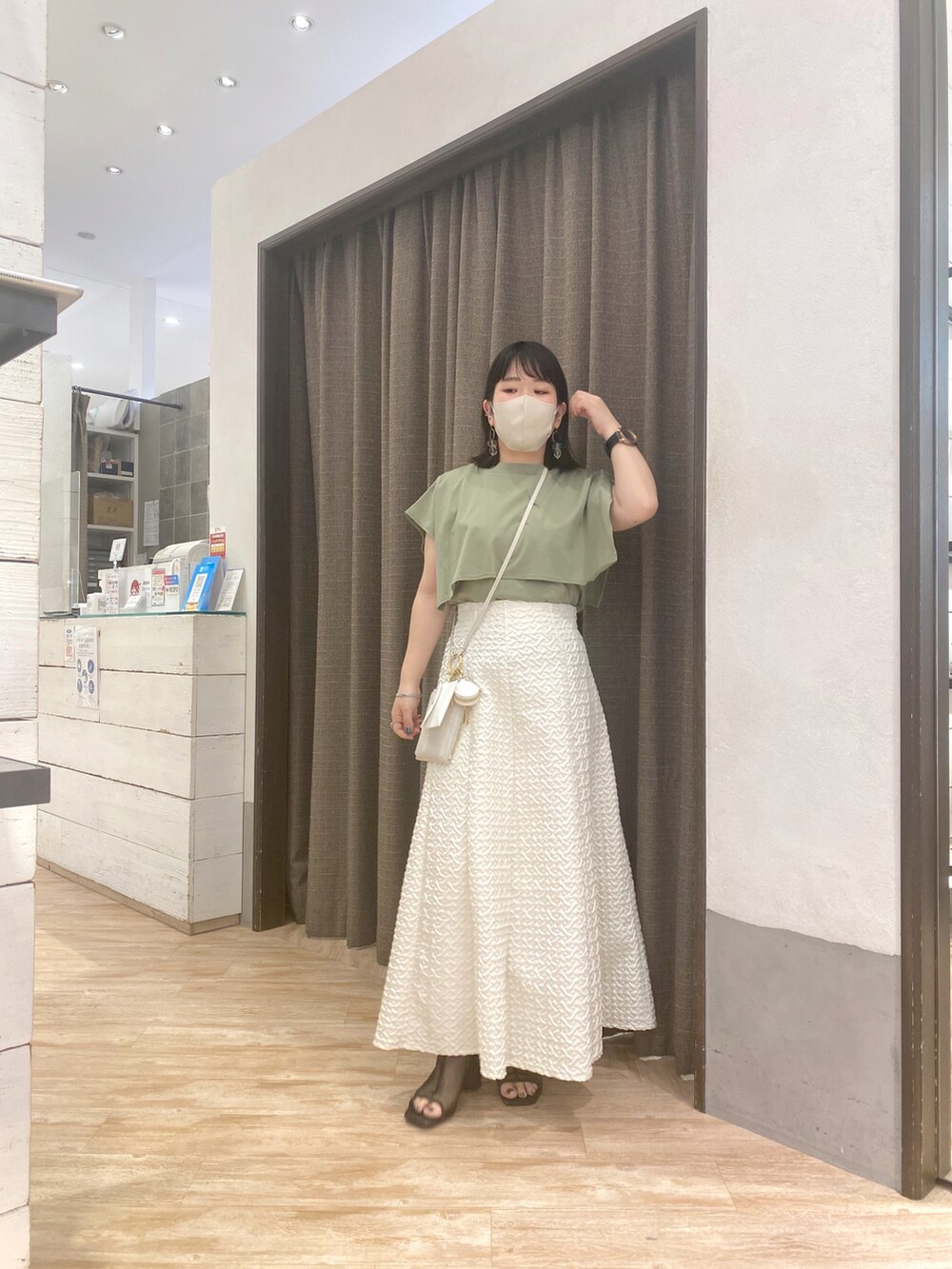 グリーン系のTシャツ/カットソー、ホワイト系のスカート、ホワイト系のショルダーバッグを着用したレディースの春コーディネートの2枚目の写真