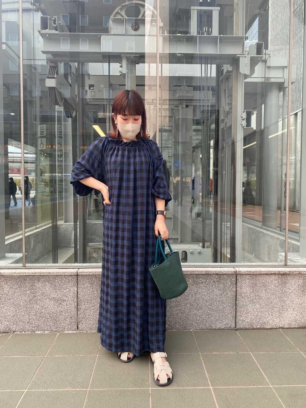 ブルー系のワンピース、グリーン系のハンドバッグ、ホワイト系のサンダルを着用したレディースの春コーディネートの2枚目の写真