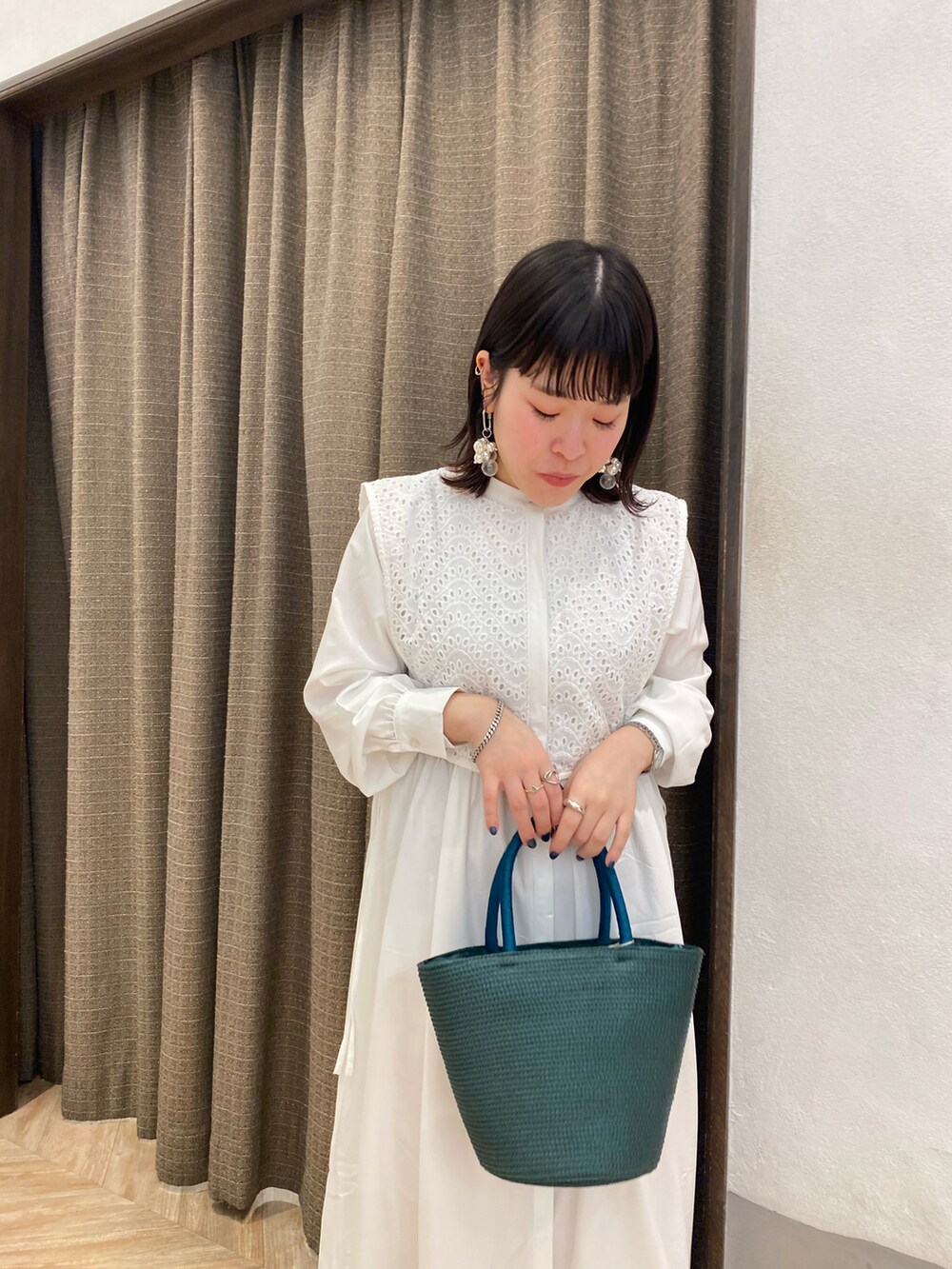 グリーン系のハンドバッグ、ホワイト系のワンピース、ホワイト系のサンダルを着用したレディースの春コーディネートの3枚目の写真