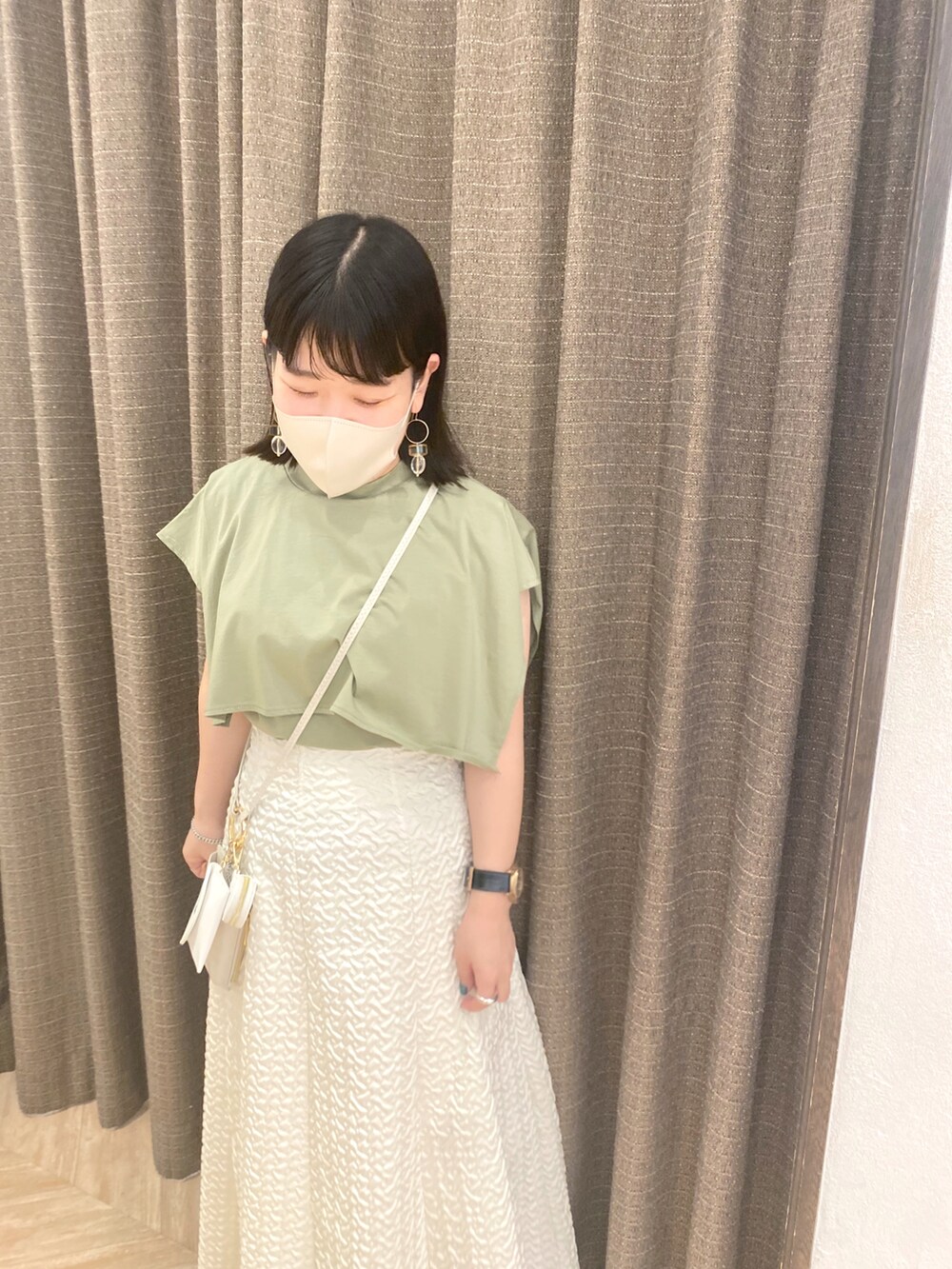 グリーン系のTシャツ/カットソー、ホワイト系のスカート、ホワイト系のショルダーバッグを着用したレディースの春コーディネートの4枚目の写真