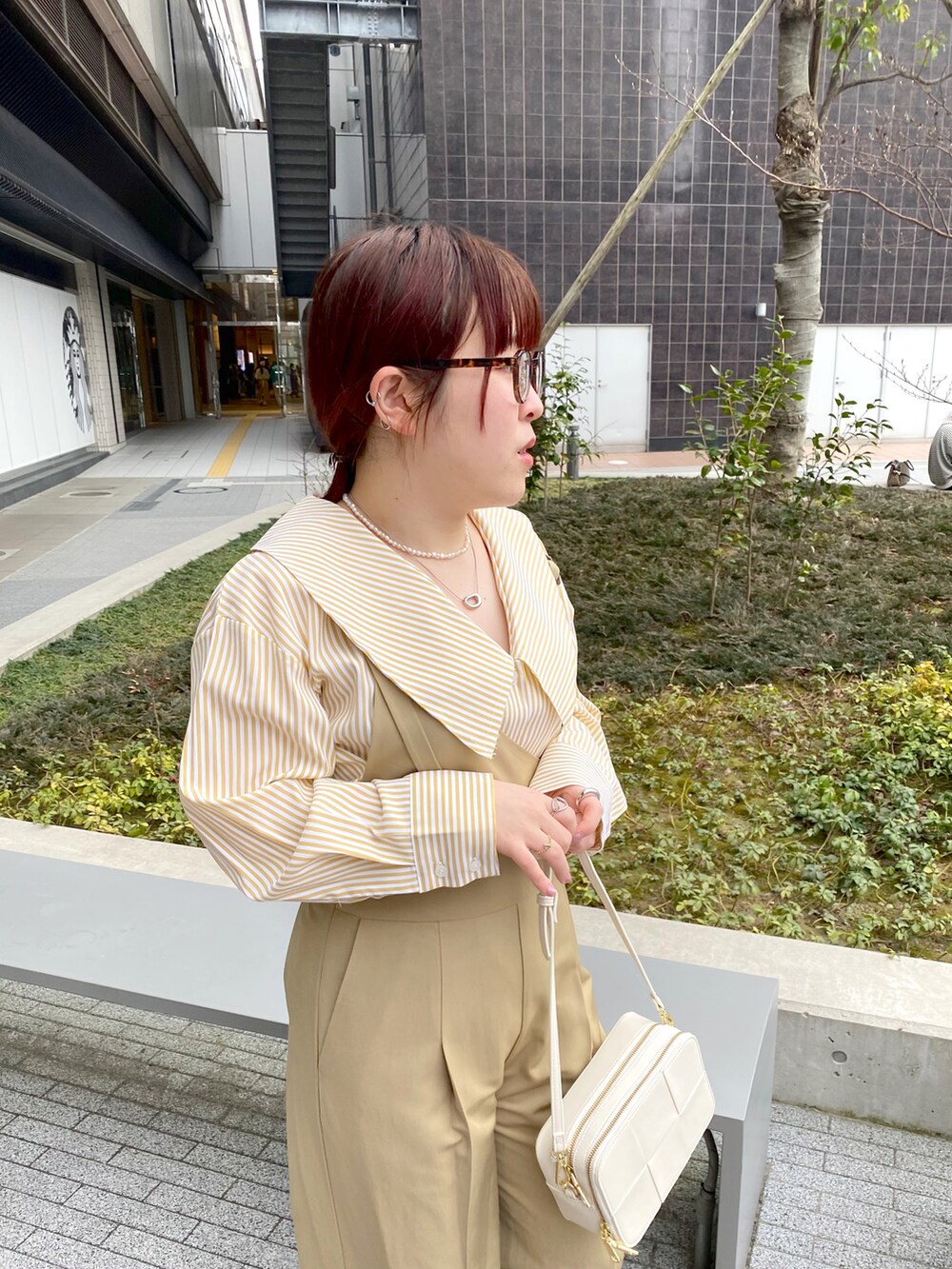 イエロー系のシャツ/ブラウス、ベージュ系のサロペット/オーバーオール、ホワイト系のショルダーバッグを着用したレディースの春コーディネートの2枚目の写真