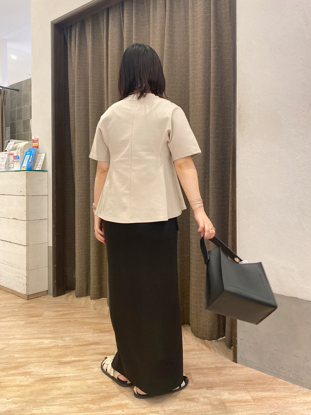 ブラック系のトートバッグ、ベージュ系のTシャツ/カットソー、ブラック系のスカートを着用したレディースの夏コーディネートの3枚目の写真