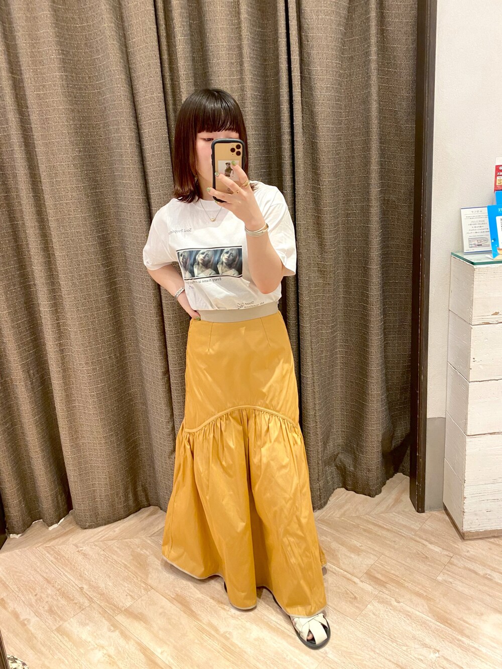 ホワイト系のTシャツ/カットソー、ベージュ系のスカート、ブラック系のカーディガン/ボレロを着用したレディースの春コーディネートの2枚目の写真