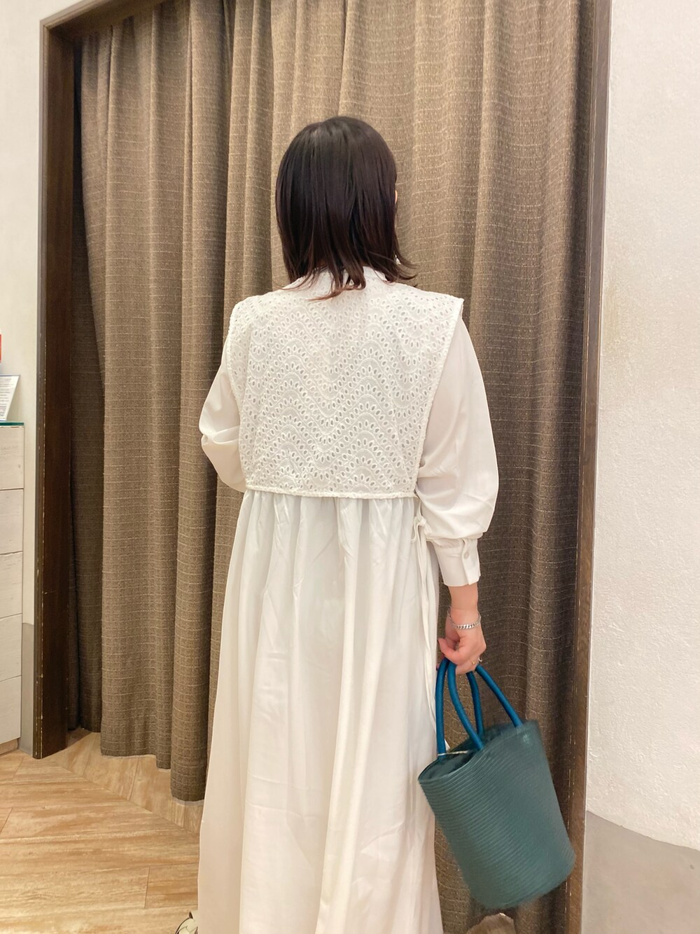 グリーン系のハンドバッグ、ホワイト系のワンピース、ホワイト系のサンダルを着用したレディースの春コーディネートの4枚目の写真