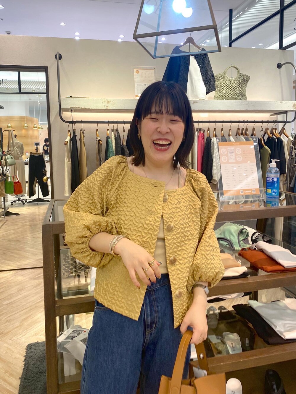 イエロー系のシャツ/ブラウス、ベージュ系のキャミソール、ブルー系のデニムパンツを着用したレディースの夏コーディネートの3枚目の写真