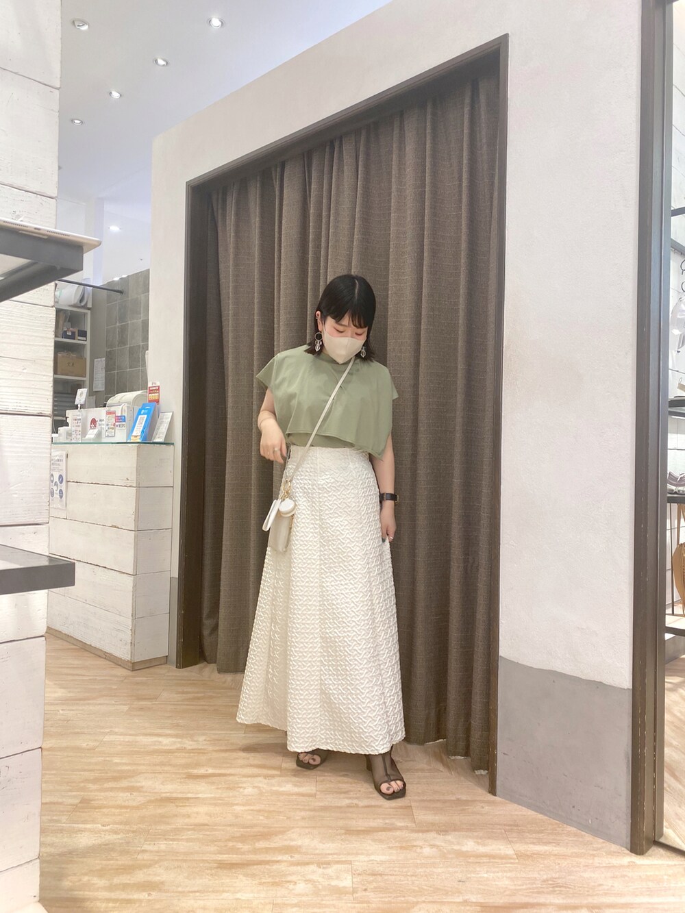 グリーン系のTシャツ/カットソー、ホワイト系のスカート、ホワイト系のショルダーバッグを着用したレディースの春コーディネートの3枚目の写真