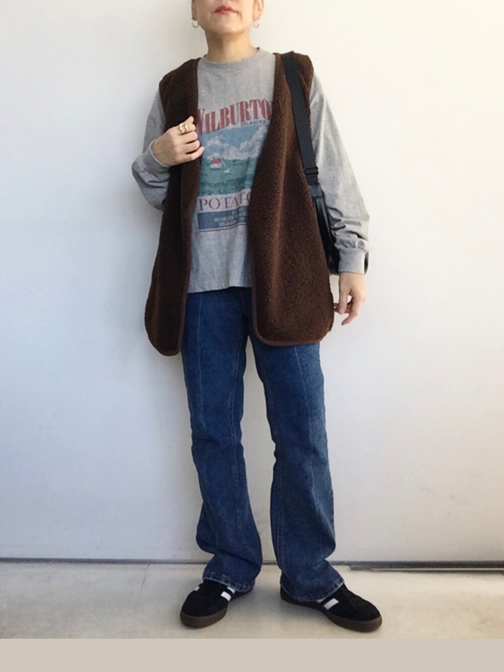 ブラウン系のベスト、グレー系のTシャツ/カットソー、ブルー系のデニムパンツを着用したレディースの秋コーディネートの2枚目の写真