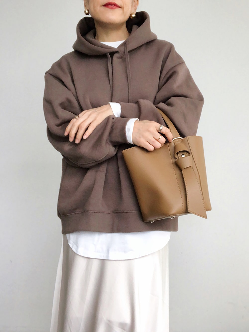 ブラウン系のパーカー、ホワイト系のスカート、ブラウン系のショルダーバッグを着用したレディースの秋コーディネートの2枚目の写真