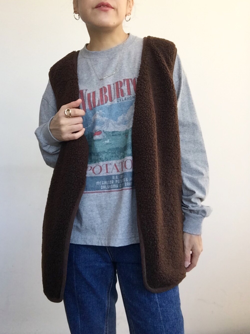ブラウン系のベスト、グレー系のTシャツ/カットソー、ブルー系のデニムパンツを着用したレディースの秋コーディネートの5枚目の写真
