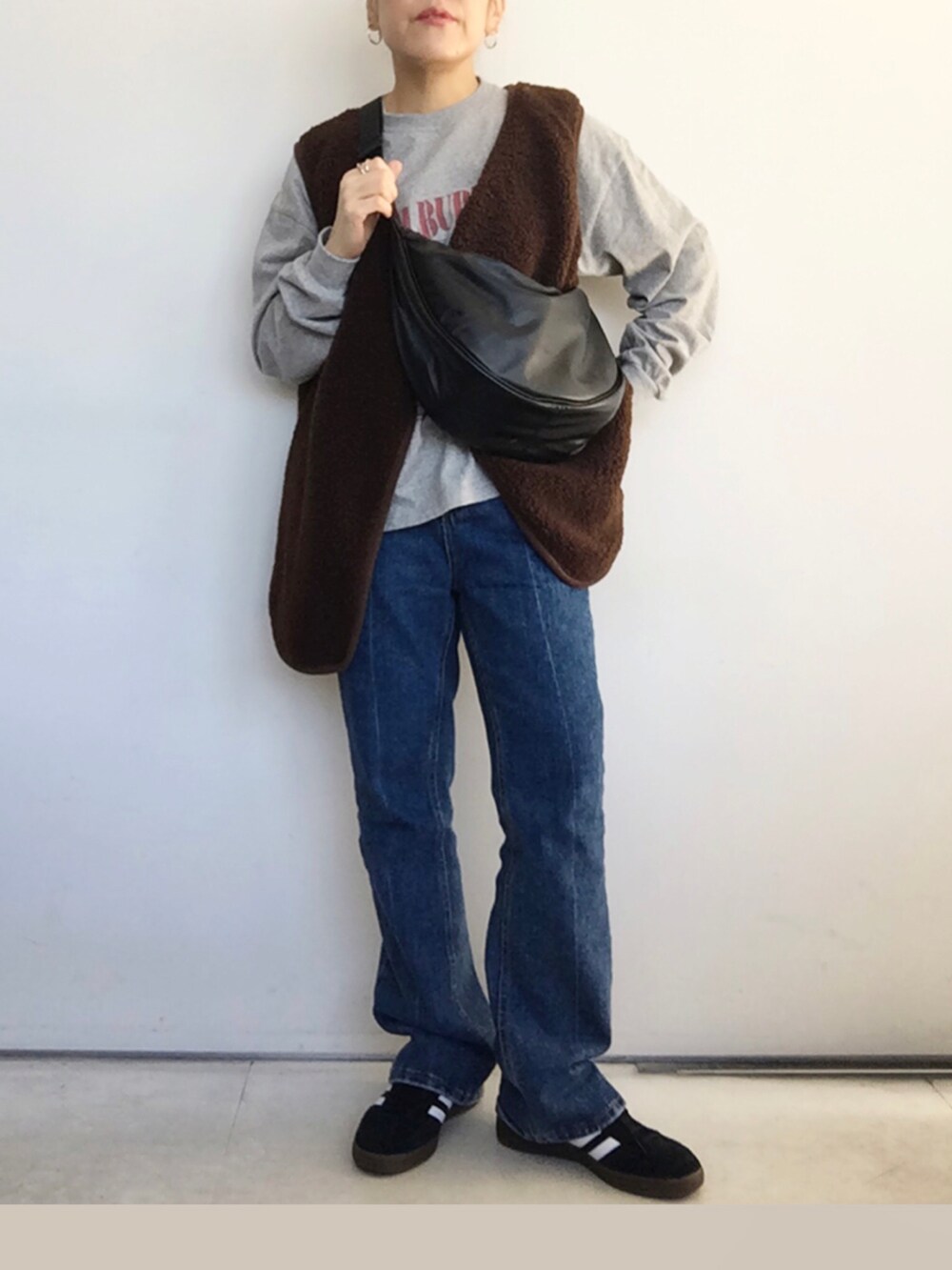 ブラウン系のベスト、グレー系のTシャツ/カットソー、ブルー系のデニムパンツを着用したレディースの秋コーディネートの4枚目の写真