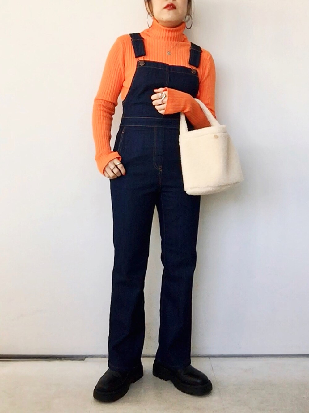 オレンジ系のニット/セーター、グリーン系のジャケット/アウター、ブルー系のサロペット/オーバーオールを着用したレディースの冬コーディネートの5枚目の写真