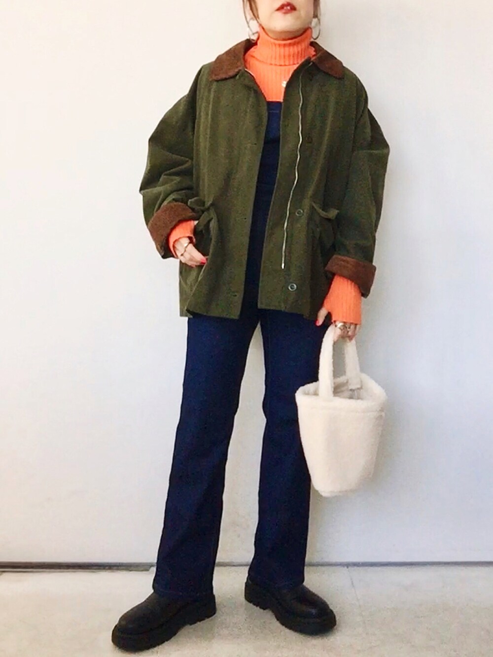 オレンジ系のニット/セーター、グリーン系のジャケット/アウター、ブルー系のサロペット/オーバーオールを着用したレディースの冬コーディネートの3枚目の写真